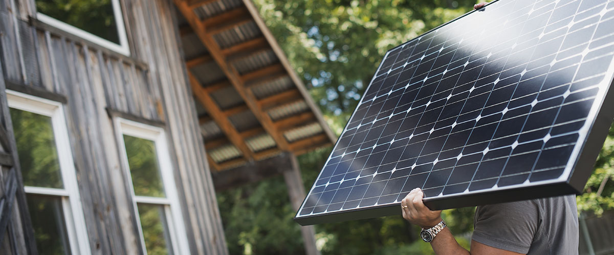 un trabajador carga con un panel solar