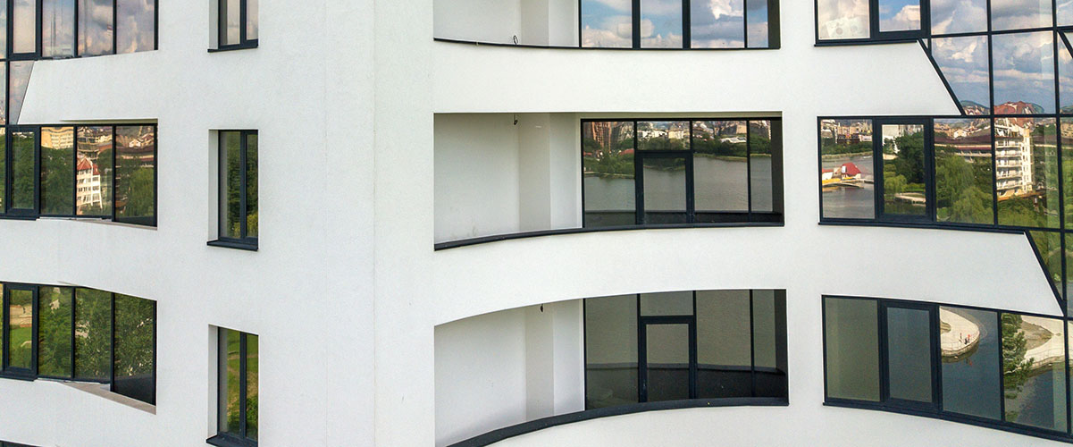 fachada blanca de un edificio con carpinterías de cristal sobre bastidores negros